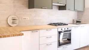A modern kitchen with white cabinets, a wooden countertop, a gas stove, an oven, and a sink. - S255 - Sirolo, new three-room apartment a stone's throw from the center (Sirolo)