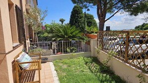 A patio with a wooden bench, a small garden area, and a car parked in the background. - S255 - Sirolo, new three-room apartment a stone's throw from the center (Sirolo)