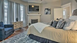 A bedroom with a bed, a ceiling fan, a fireplace, a TV, and a window with curtains. - Paradise at Piedmont Park & Near Atlanta Attractions (Atlanta)