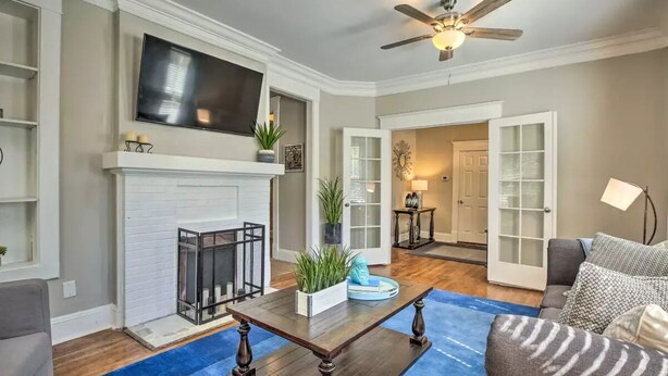 A living room with a fireplace, a television mounted above it, a ceiling fan, and a blue rug. - Paradise at Piedmont Park & Near Atlanta Attractions (Atlanta)
