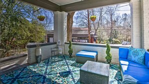 A covered patio area with patterned flooring, outdoor seating, and hanging flower baskets. - Paradise at Piedmont Park & Near Atlanta Attractions (Atlanta)