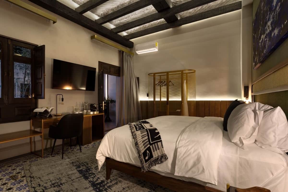 A hotel room with a bed, desk, chair, TV, and a wardrobe.