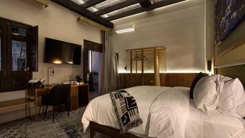 A hotel room with a bed, desk, chair, TV, and a wardrobe.
