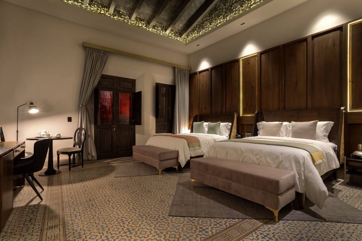 A hotel room with a large bed, a desk, a chair, and a small table.