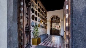 Entrada de un hotel con piso a cuadros, una pared con decoraciones circulares y rectangulares, y una puerta de madera.