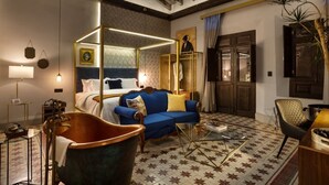 Una habitación con una cama con dosel, un sofá azul, una bañera antigua y un suelo con estampado de estrellas.
