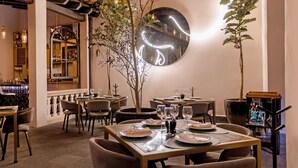 Restaurante con mesas dispuestas para comer, un espejo grande en la pared y una zona de bar al fondo.