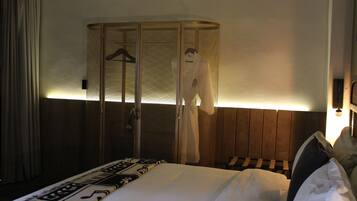 A hotel room with a bed, a hanging robe, and a wooden headboard.