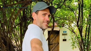 Ein Mann in weißem Hemd und blauen Shorts hält die Hand einer anderen Person.