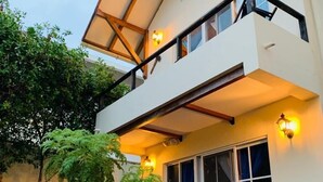 Ein zweistöckiges Gebäude mit Balkon, großen Fenstern und Außenbestuhlung.
