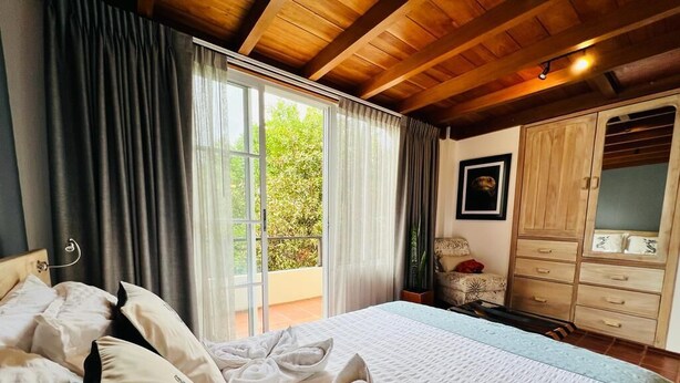 Ein Schlafzimmer mit einem großen Bett, einem Holzschrank und einer Schiebetür zum Balkon.