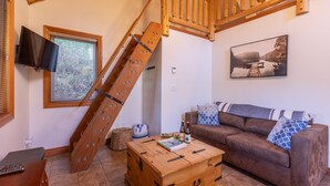 Ein Wohnzimmer mit einer Holztreppe, einem Sofa, einer Holzkiste und einem Fernseher.