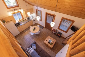 Une cuisine moderne avec un coin repas, un plafond en bois et de grandes fenêtres.