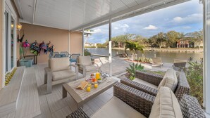 A spacious outdoor patio with a view of a river, wicker furniture, and a table set with breakfast. - NEW Heated Salt Pool & Spa on Waterfront Canal (Tampa)