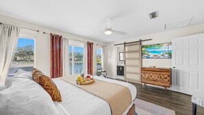 A hotel room with a bed, a breakfast tray, a view of a pool, and a sliding door to the outside. - NEW Heated Salt Pool & Spa on Waterfront Canal (Tampa)