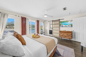 Habitación de hotel con cama, bandeja de desayuno, vista a una piscina y puerta corrediza al exterior.