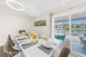 Un comedor con una mesa preparada para cuatro personas, vista a un cuerpo de agua y un cuadro decorativo de peces en la pared.