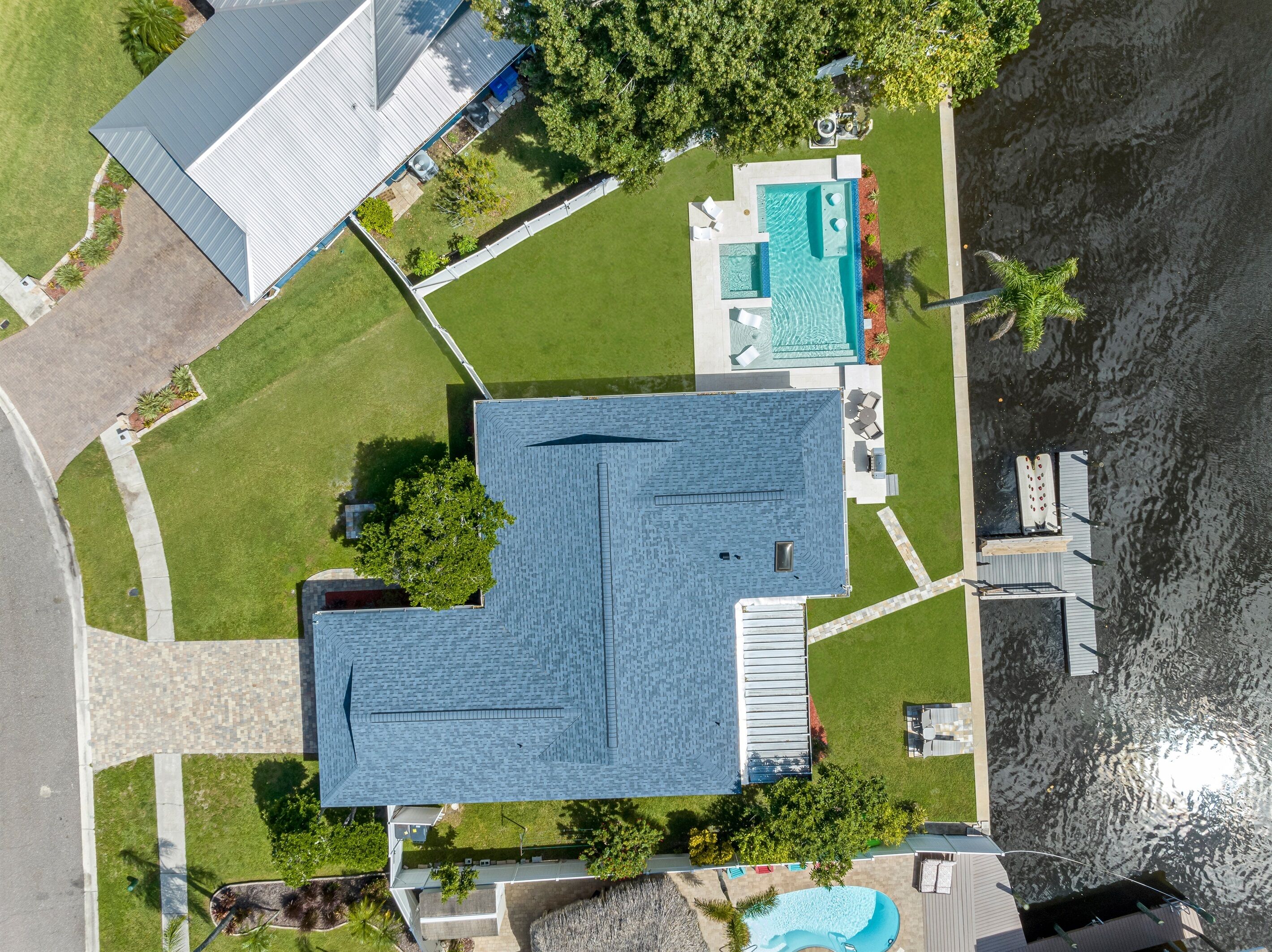 An aerial view of a house with a swimming pool, a covered patio, and a boat dock.