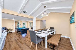 A spacious living area with a pool table, a dining table set for six, and a pool. - NEW Heated Salt Pool & Spa on Waterfront Canal (Tampa)