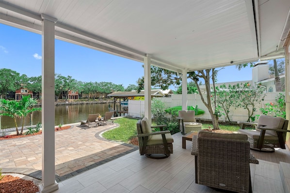 An outdoor patio area with wicker furniture, a view of a lake, and a covered walkway.