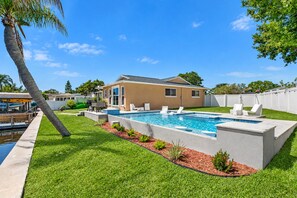 A residential property with a swimming pool, a covered patio, and a well-maintained lawn. - NEW Heated Salt Pool & Spa on Waterfront Canal (Tampa)