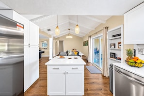A modern kitchen with white cabinetry, a central island, and pendant lighting. - Waterfront | Heated Salt Pool & Spa (Tampa)