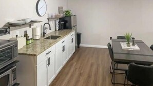 Una cucina moderna con mobili bianchi, un piano di lavoro in granito e un'area pranzo con tavolo e sedie.