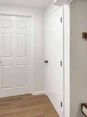 Um corredor com uma porta branca e um candeeiro fixado na parede.