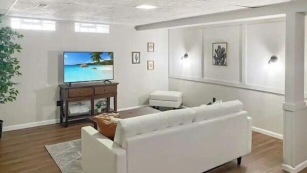 Un soggiorno con un divano bianco, una televisione su un mobile in legno e un tavolino con oggetti decorativi.