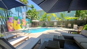 Ein Poolbereich mit Liegestühlen, einem kleinen Pool und Sonnenschirmen.