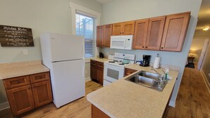 Une cuisine avec des meubles de rangement en bois, un réfrigérateur blanc, une cuisinière, un four à micro-ondes et un évier.