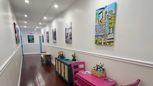 A hallway with a wooden floor, a pink table with chairs, a blue cabinet, and wall art. - Duval Street Suites full kitchen, free parking, & heated pool (Key West)