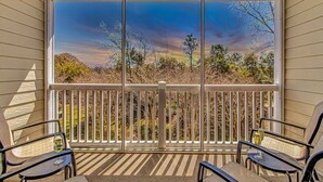 A covered outdoor area with a view of trees and sky through large windows.