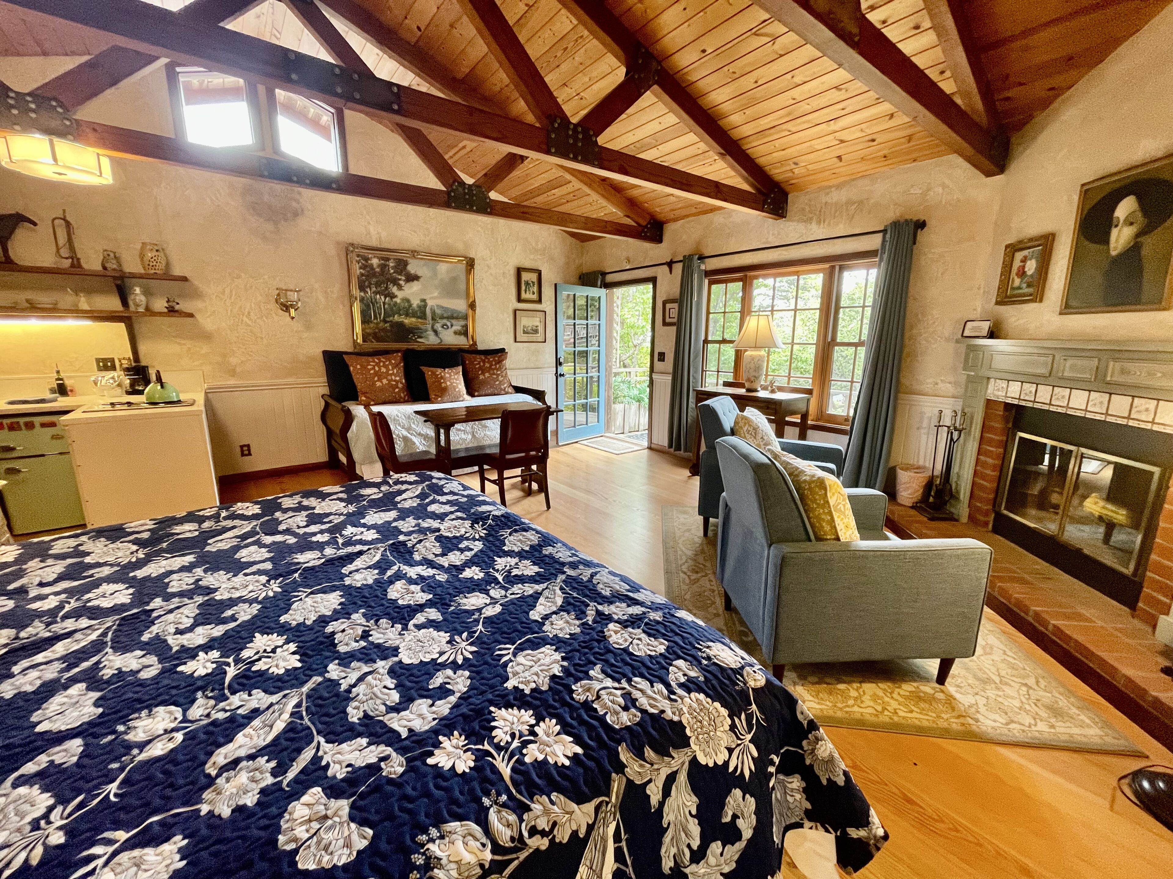 A spacious bedroom with a large bed, a fireplace, and a view of the outdoors.