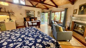 A spacious bedroom with a large bed, a fireplace, and a view of the outdoors.