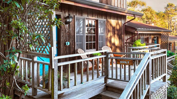 A rustic wooden house with a porch, wooden steps, and a sign that reads "QUILT". - Rendezvous Mendocino (Gualala)