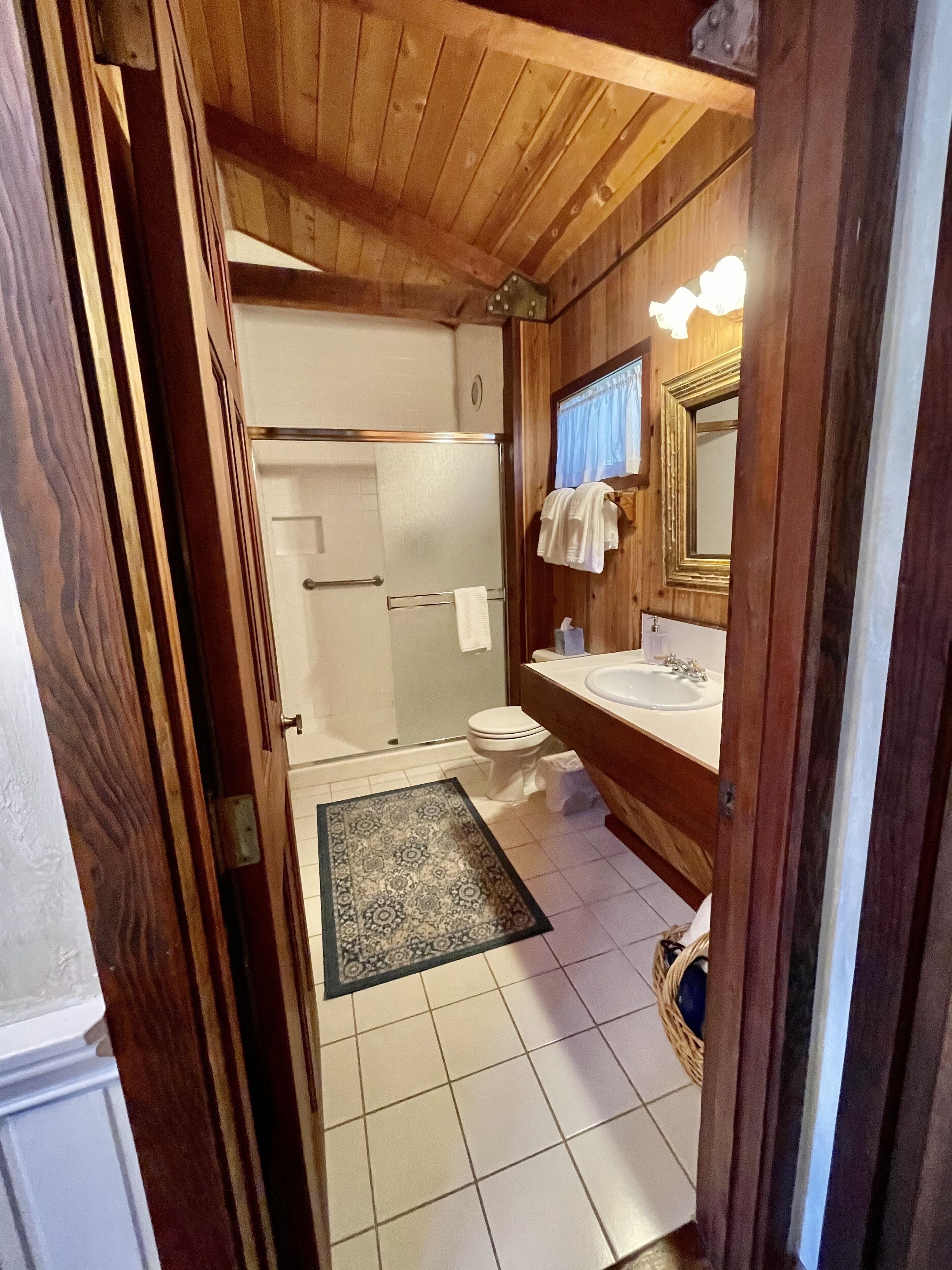 Une salle de bain en bois avec une douche, des toilettes et un lavabo.