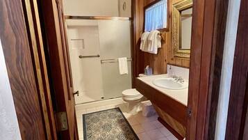 Une salle de bain en bois avec une douche, des toilettes et un lavabo.