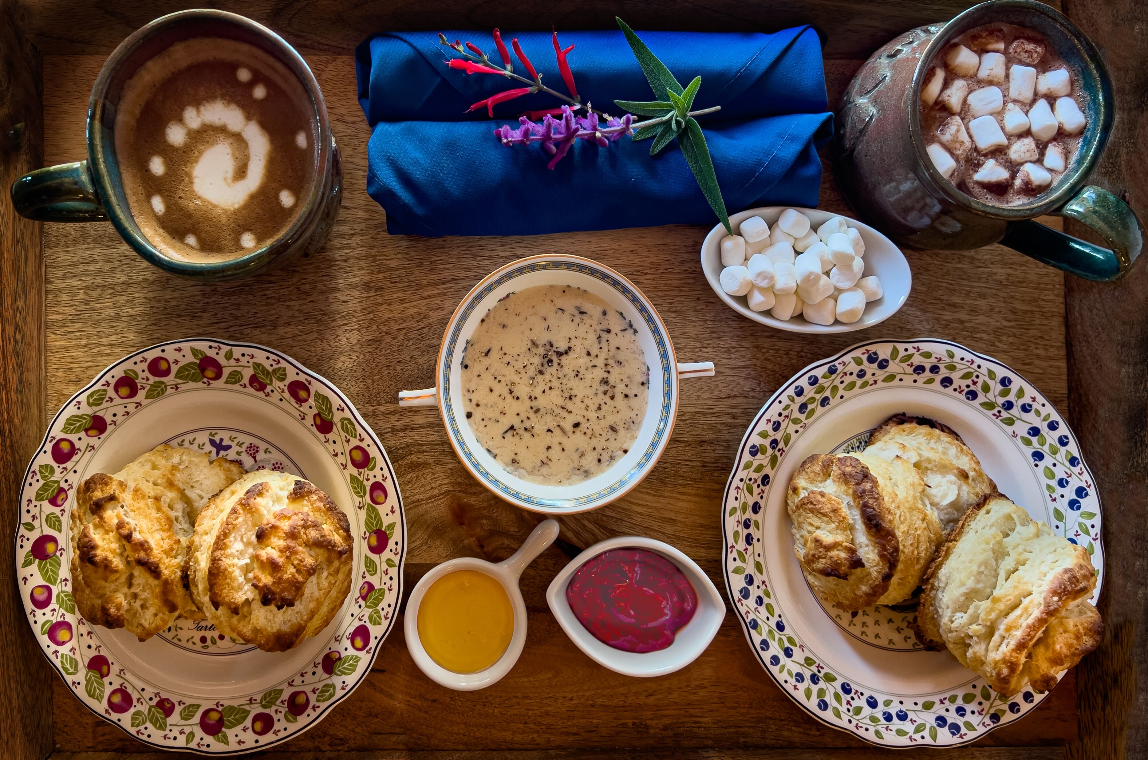 Una bandeja amb una tassa de cafè, un got de xocolata calenta i dues platades de scones amb mantequilla i melmelada.