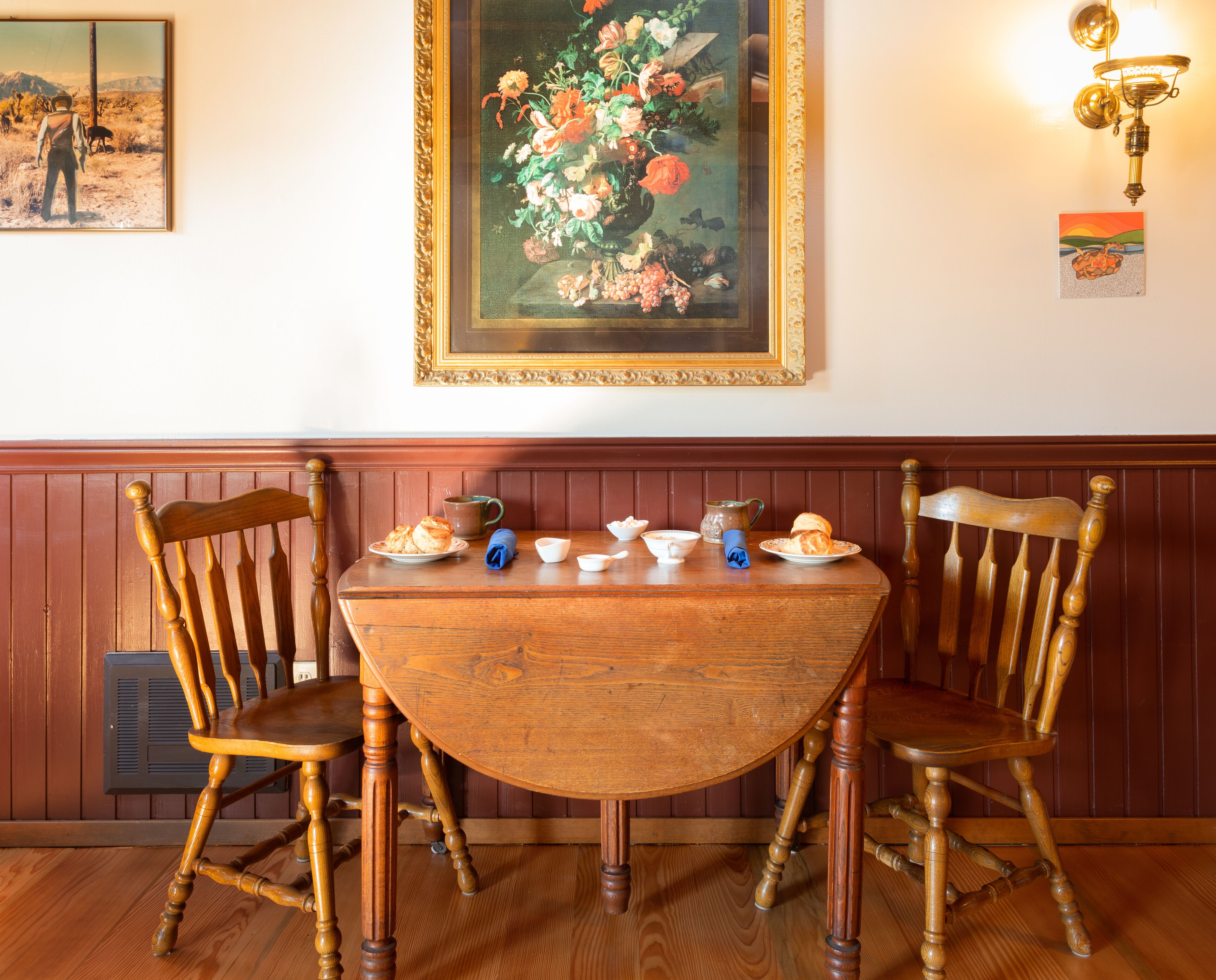Une table à manger avec des chaises, un tableau et un lustre.