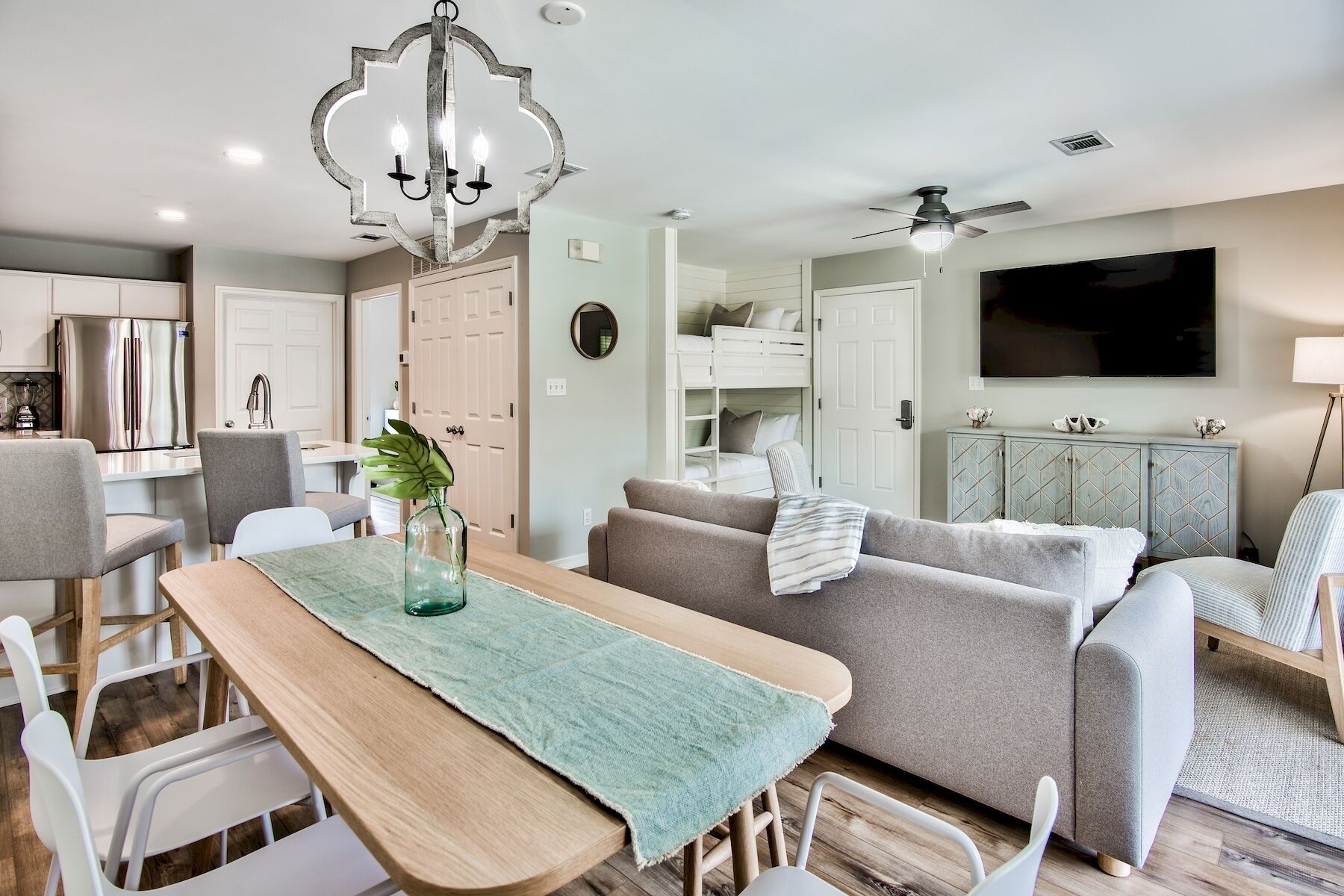 A modern living room with a dining area, a built-in TV, and a ceiling fan.