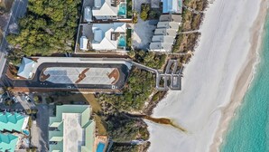 Vista aérea de un hotel costero con varias edificaciones, un estacionamiento y una playa.