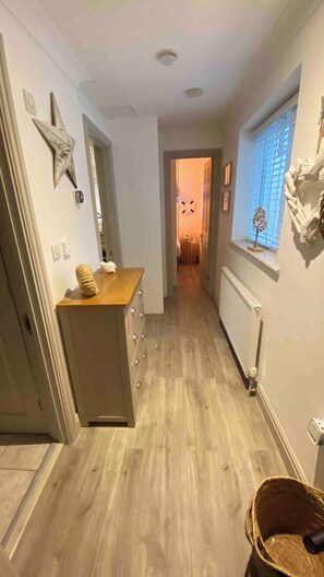 A narrow hallway with a wooden floor, a radiator on the right, and a star decoration on the left.