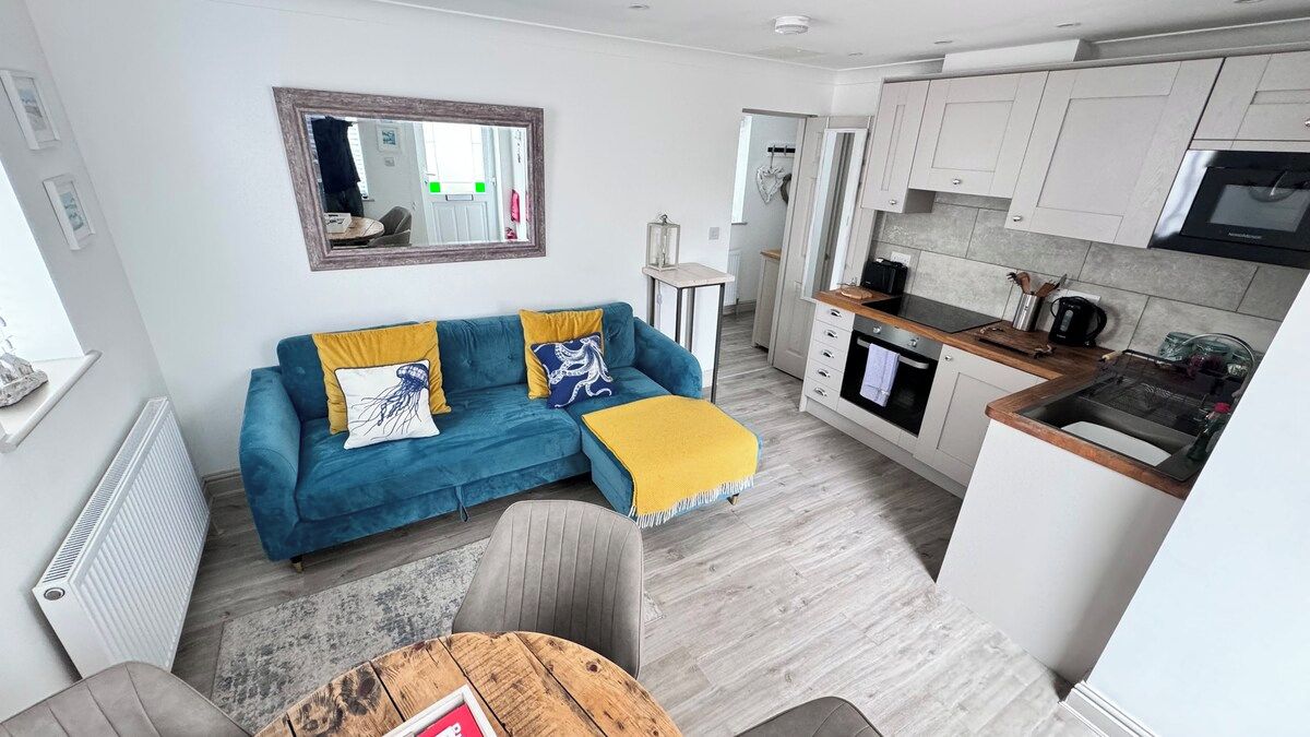 Ein gemütlicher Wohnbereich mit Sofa, Esstisch, Küchenzeile und Spiegel.