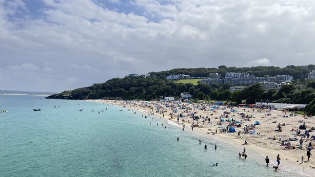 A beach with clear turquoise water, sandy shore, and buildings on a hillside. - St James Rest - sleeps 4 guests  in 2 bedrooms (St Ives)