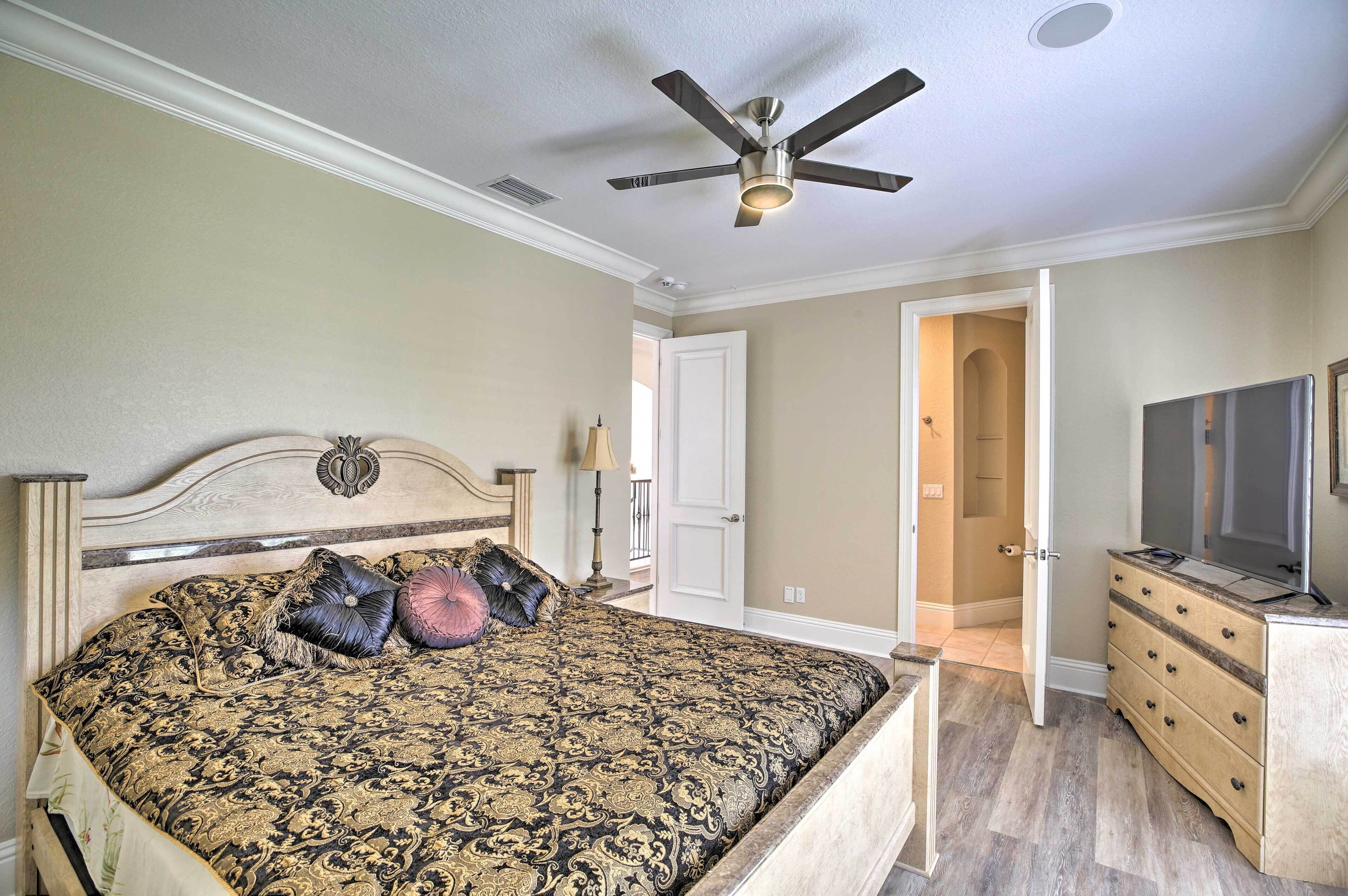 A bedroom with a bed, a ceiling fan, a dresser, and a television.