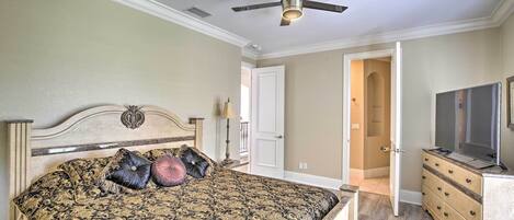 A bedroom with a bed, a ceiling fan, a dresser, and a television.