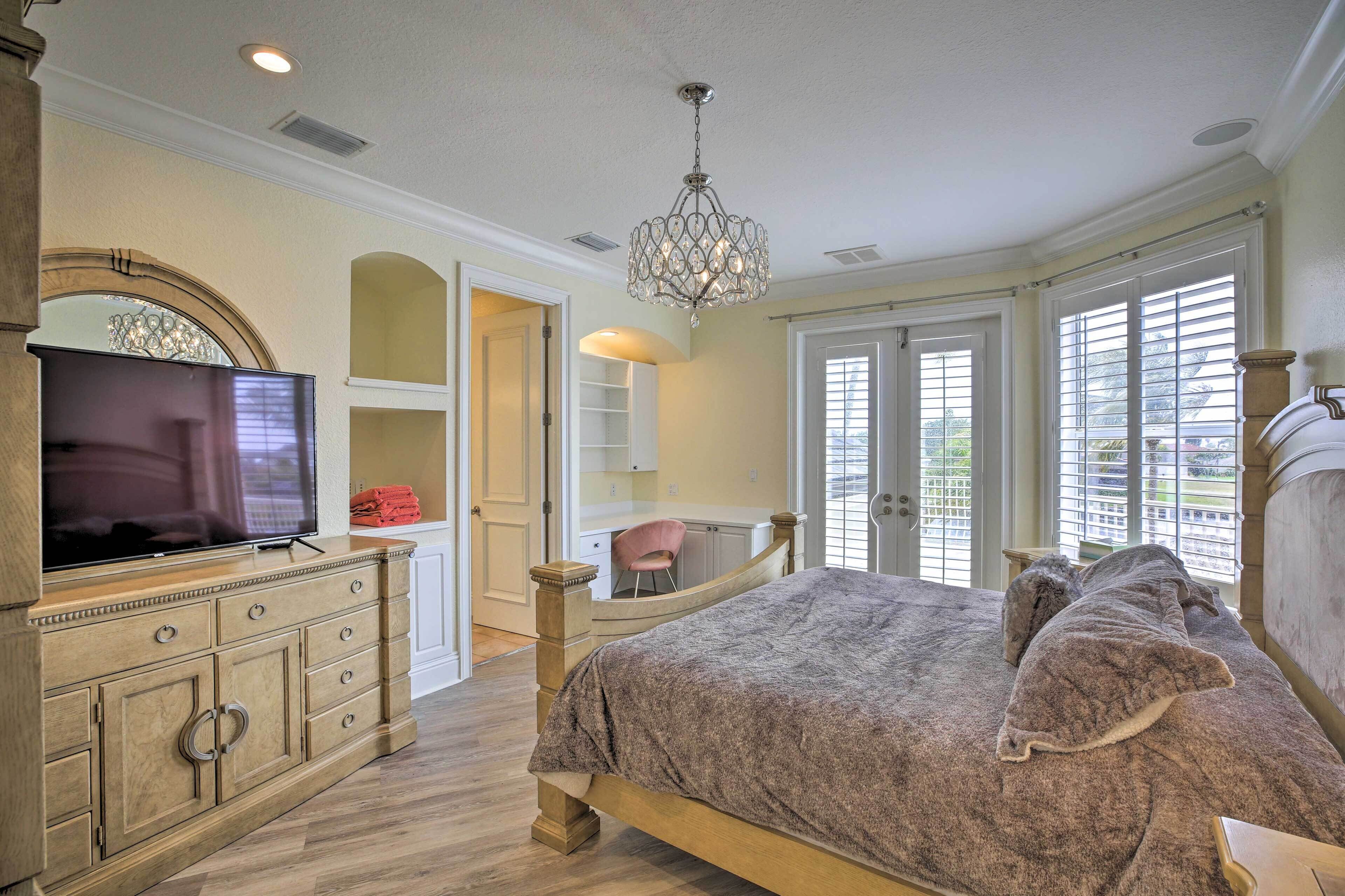 A bedroom with a bed, a dresser, a TV, and a chandelier.