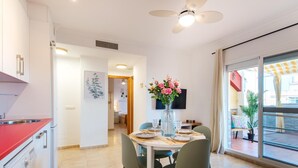A modern kitchen with a red countertop, a dining area with a table and chairs, and a large window with a view of the outside. - Cosy Urban Penthouse In The Heart Of Fuengirola (FUENGIROLA)