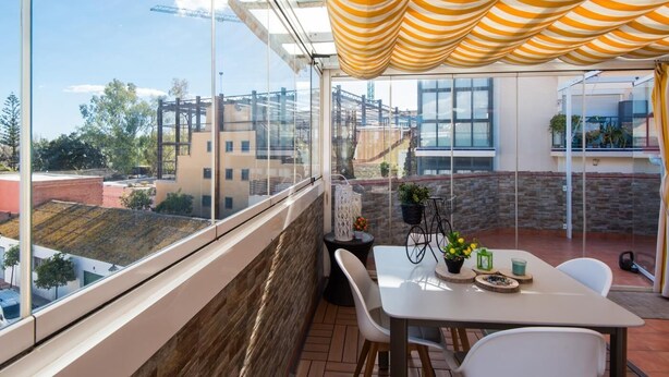 A balcony with a table and chairs, a view of buildings, and a striped canopy. - Cosy Urban Penthouse In The Heart Of Fuengirola (FUENGIROLA)